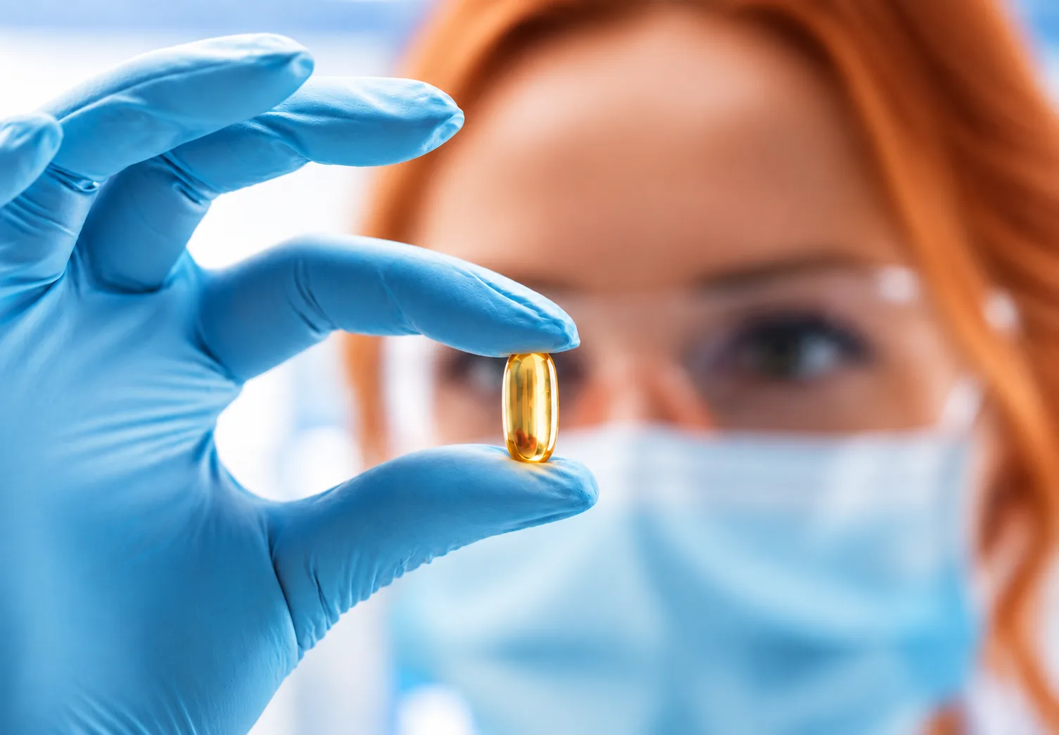 Scientist holding a softgel capsule - who can hold a drug registration in Malaysia